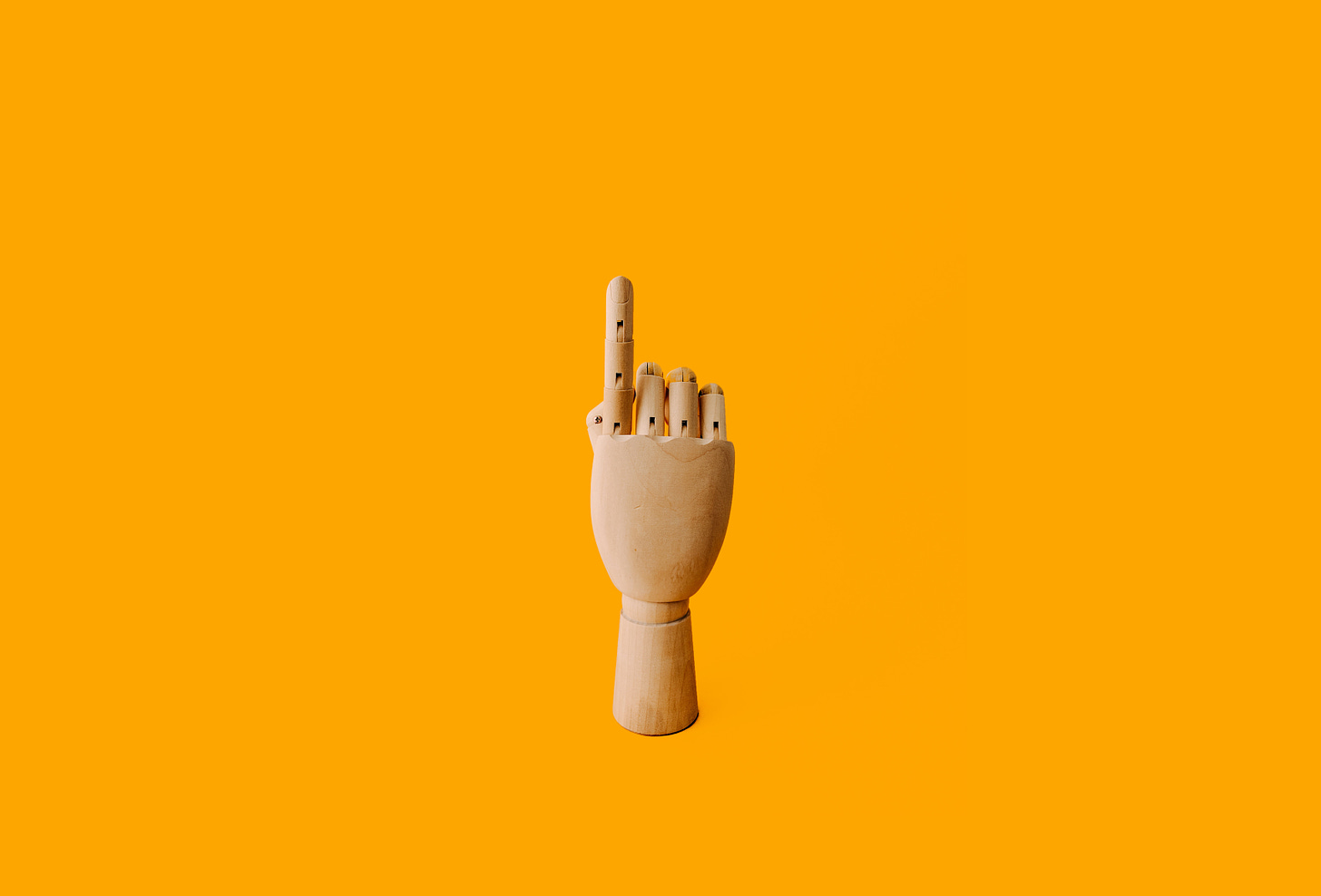 hand with index finger pointing upward in front of orange background