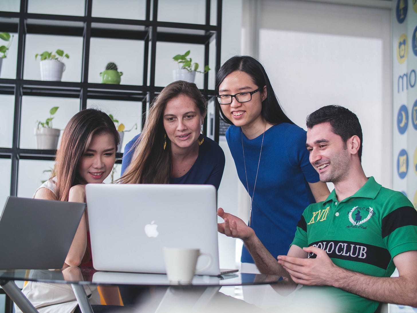 A group of diverse people talking in front of a laptop screen. A group of diverse people talking in front of a laptop screen.