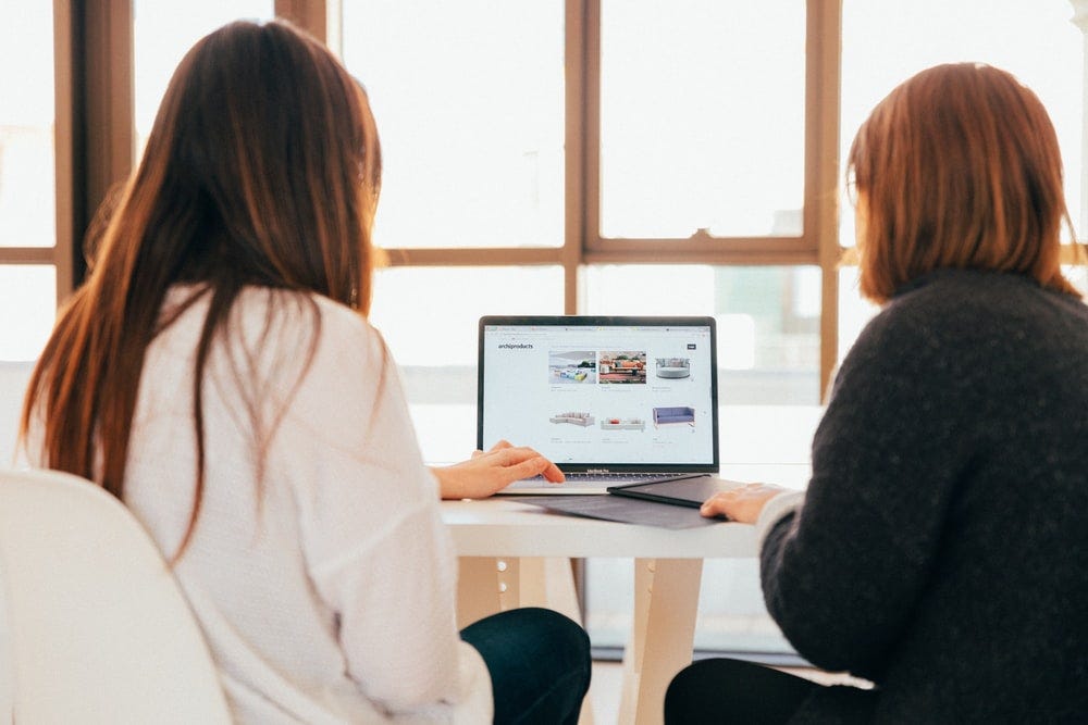 two women talking while looking at laptop computer two women talking while looking at laptop computer
