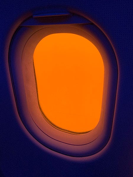 A photo of a window on an airplane where the wall is dark purple and the window is only orange. A photo of a window on an airplane where the wall is dark purple and the window is only orange.