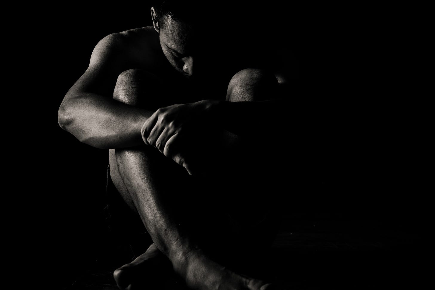 black and white photo of a depressed man crouched in the dark for article by Larry G. Maguire black and white photo of a depressed man crouched in the dark for article by Larry G. Maguire