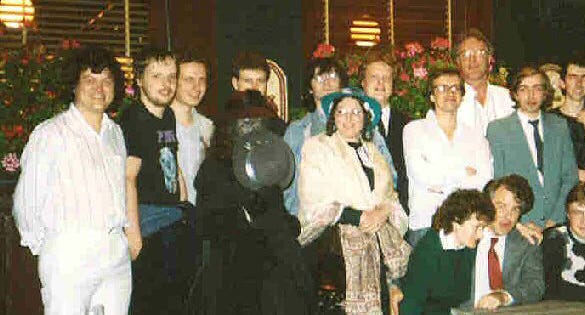 Photograph of a group of computer professionals, with two women in nineteenth century clothing in the center, one veiled and concealing her face with a hat. Photograph of a group of computer professionals, with two women in nineteenth century clothing in the center, one veiled and concealing her face with a hat.