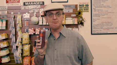 Man in a supermarket holding an energy drink, saying "Big energy" to camera.