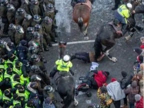 Toronto Police Mounted Unit officers push through a crowd at the Freedom Convoy protest in Ottawa and trample at least two demonstrators on Friday, Feb. 18, 2022.