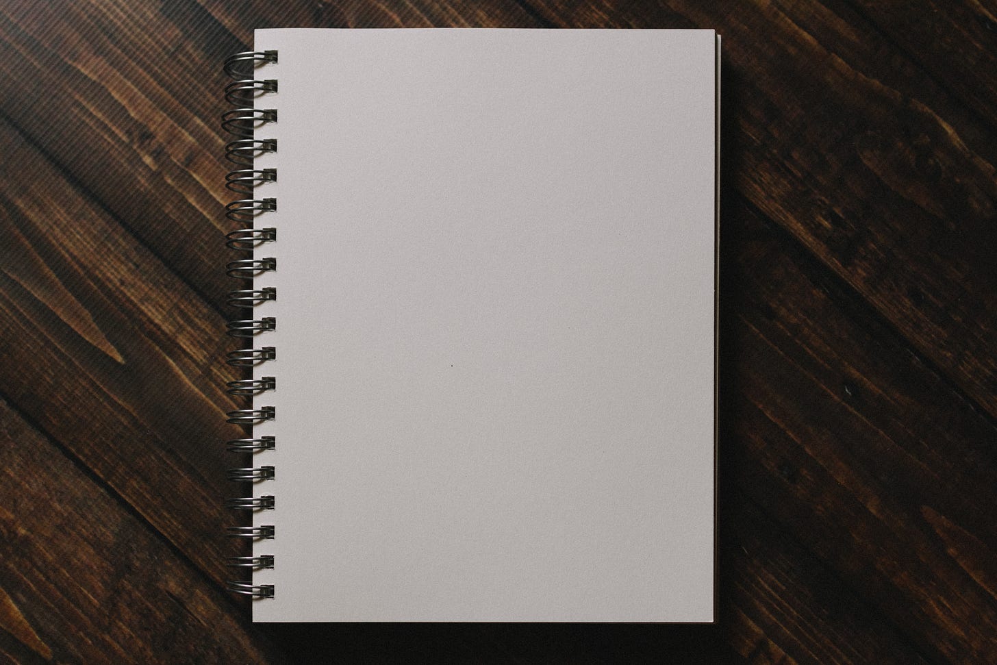 White notebook on brown wooden table. White notebook on brown wooden table.