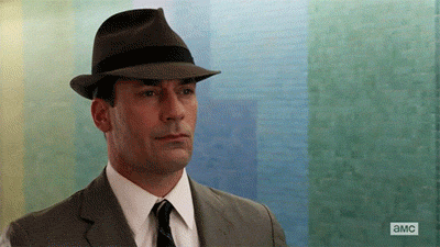 Don Draper rides on a people mover in LAX with a stoic expression. [gif]