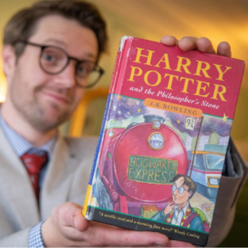 A man holds a first edition Harry Potter book. A man holds a first edition Harry Potter book.
