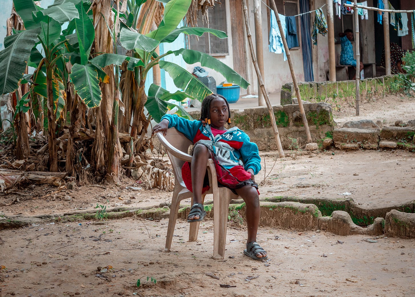A young girl sitting on a chair staring blankly into space in Ediba: A photo by David Elikwu