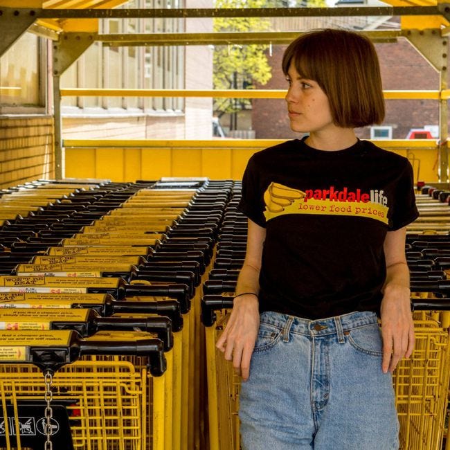Chantelle Rose poses with grocery carts at a No Frills in the Parkdale neighbourhood of Toronto. The anonymous Instagram account Parkdale Life showed its love for Vi's No Frills, which recently reopened, by selling No-Frills-themed T-shirts with proceeds going to the Parkdale Community Food Bank. Chantelle Rose poses with grocery carts at a No Frills in the Parkdale neighbourhood of Toronto. The anonymous Instagram account Parkdale Life showed its love for Vi's No Frills, which recently reopened, by selling No-Frills-themed T-shirts with proceeds going to the Parkdale Community Food Bank.