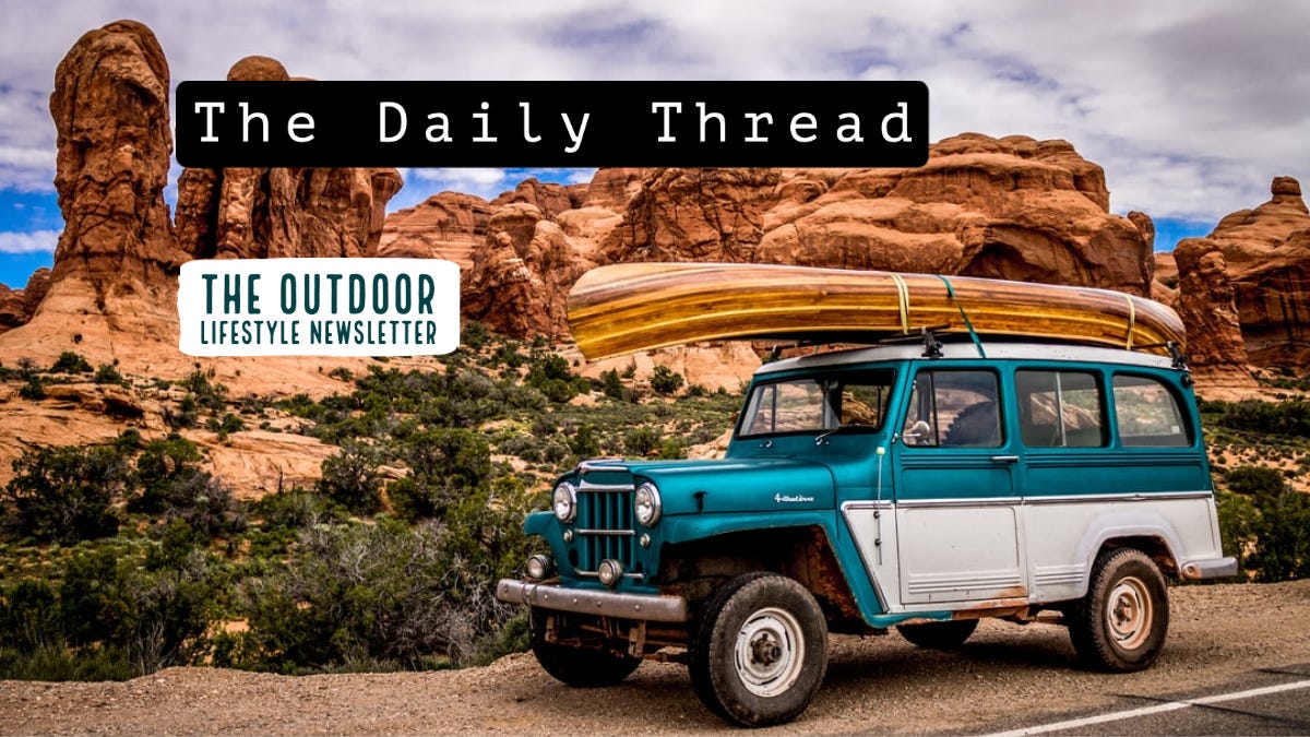 Old truck with canoe strapped to top in front of mountains