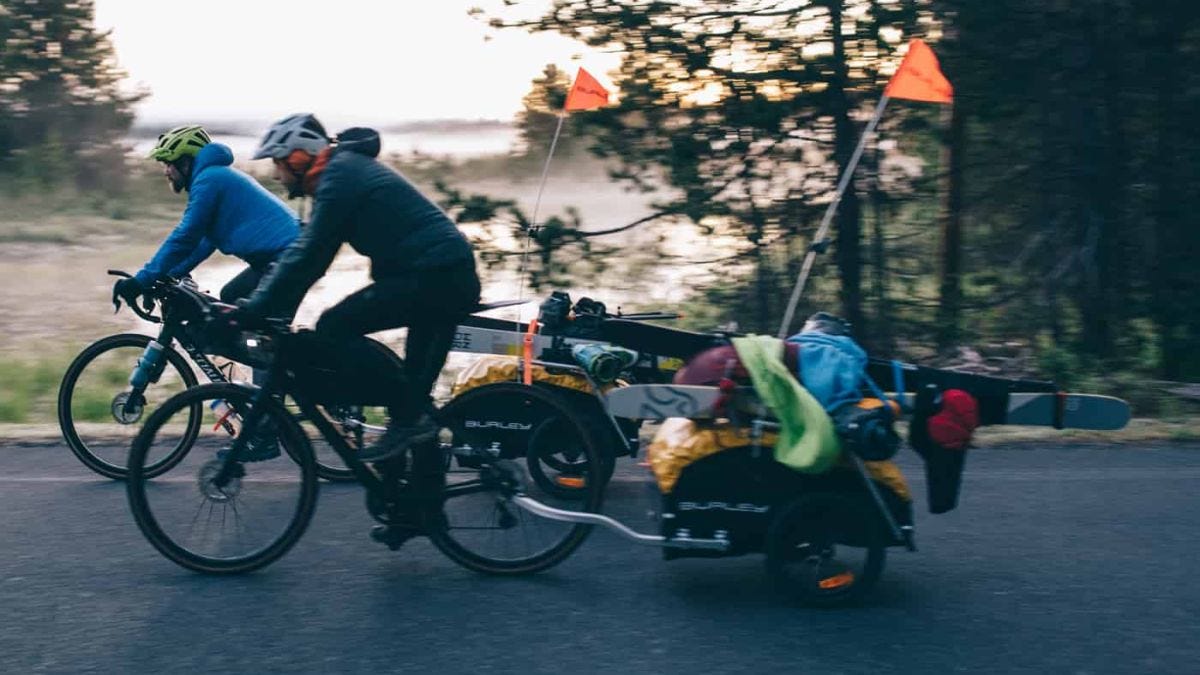 two men bike with ski trailers attached to their bikes