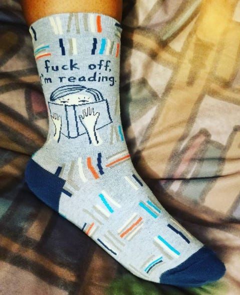 photo of a sock on my foot. The sock is mostly blue with images of books and a person reading with the text, "fuck off I'm reading" photo of a sock on my foot. The sock is mostly blue with images of books and a person reading with the text, "fuck off I'm reading"