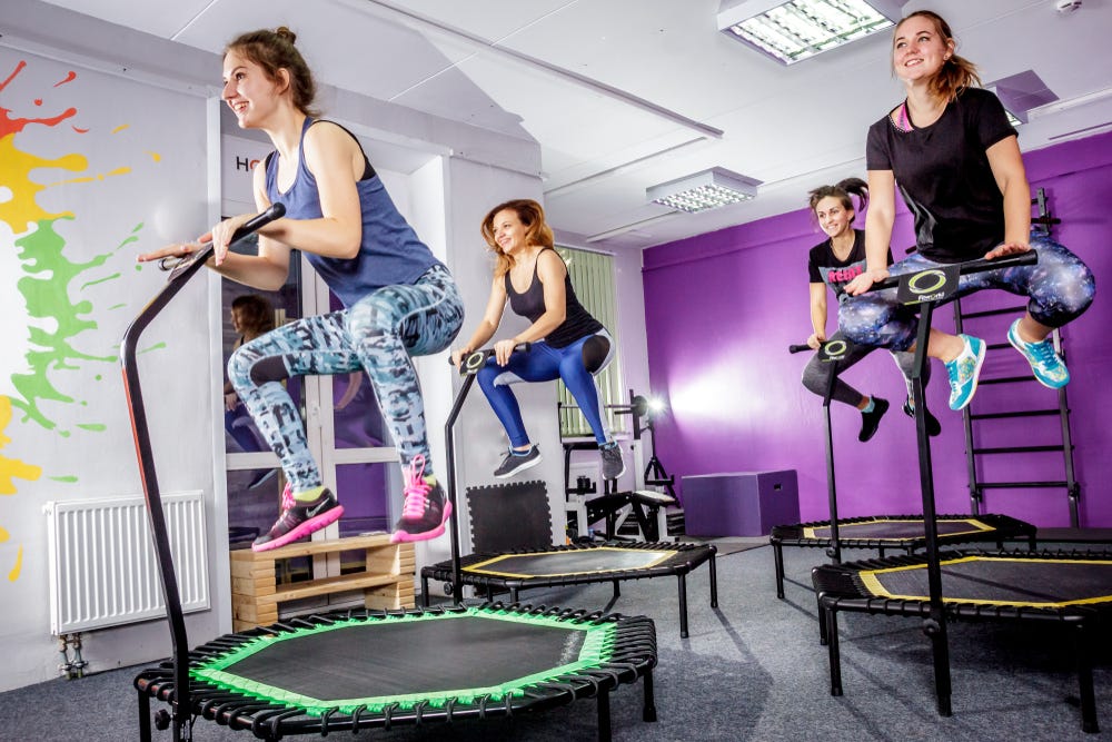 Group of women happily exercising on hexagonal trampolines with stability bars Group of women happily exercising on hexagonal trampolines with stability bars