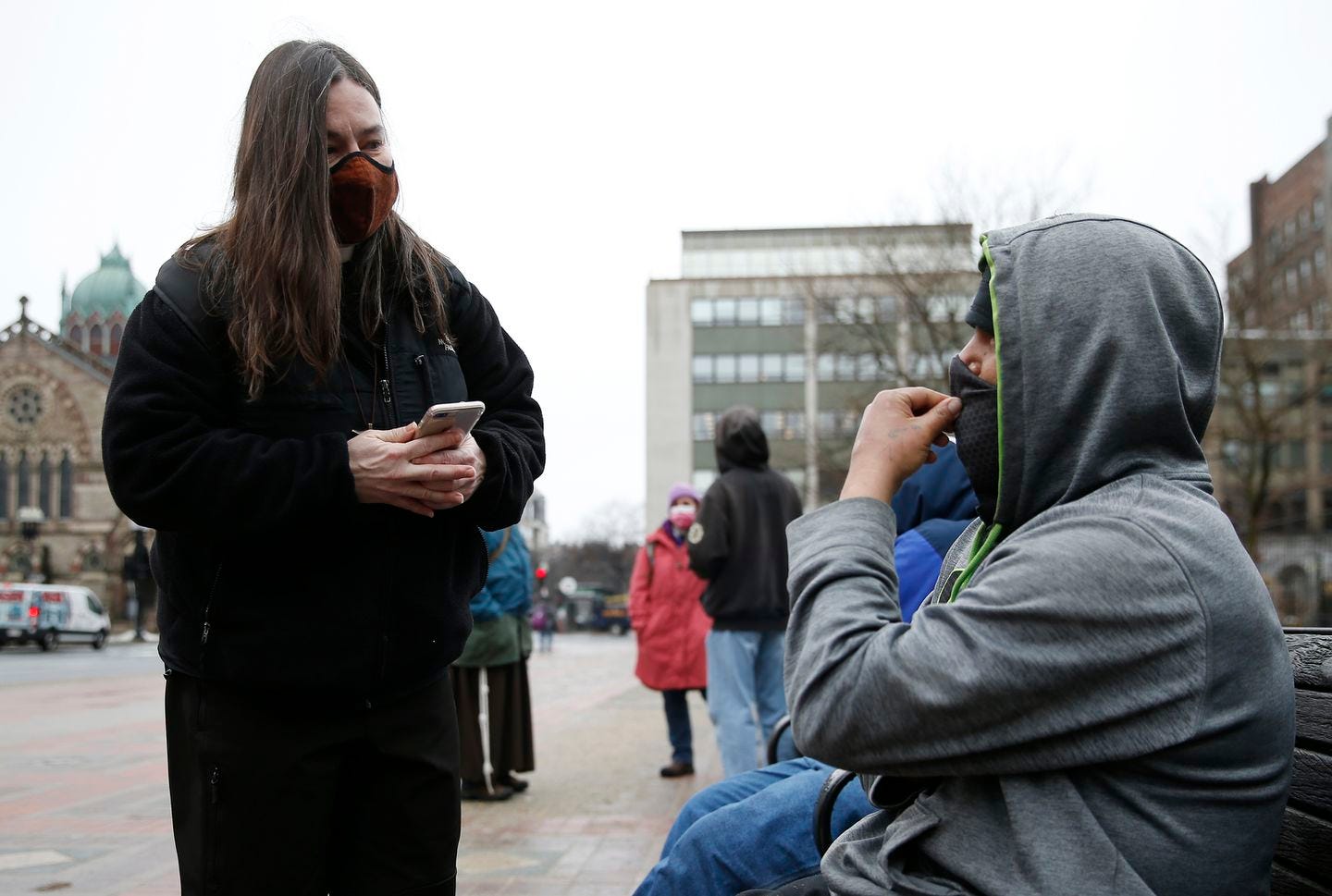 Boston, MA -- 3/1/21 -- Lisa Loughlin, a chaplain who is part of 'Common Cathedral' an organization which has ecumenical services on Boston Common, offers her phone to a homeless man in Copley Square who had asked to use it so he could try and call a family member. (Jessica Rinaldi/Globe Staff) Boston, MA -- 3/1/21 -- Lisa Loughlin, a chaplain who is part of 'Common Cathedral' an organization which has ecumenical services on Boston Common, offers her phone to a homeless man in Copley Square who had asked to use it so he could try and call a family member. (Jessica Rinaldi/Globe Staff)