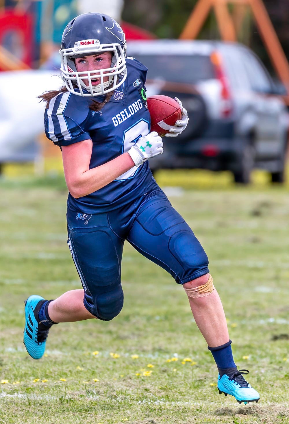 woman in blue football jersey holding football