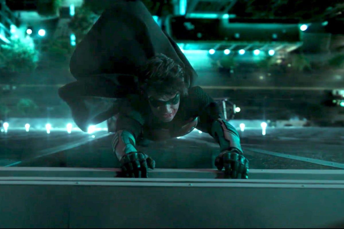 Jason Todd (Curran Walters) hangs by his hands from the edifice of a building, in Titans.