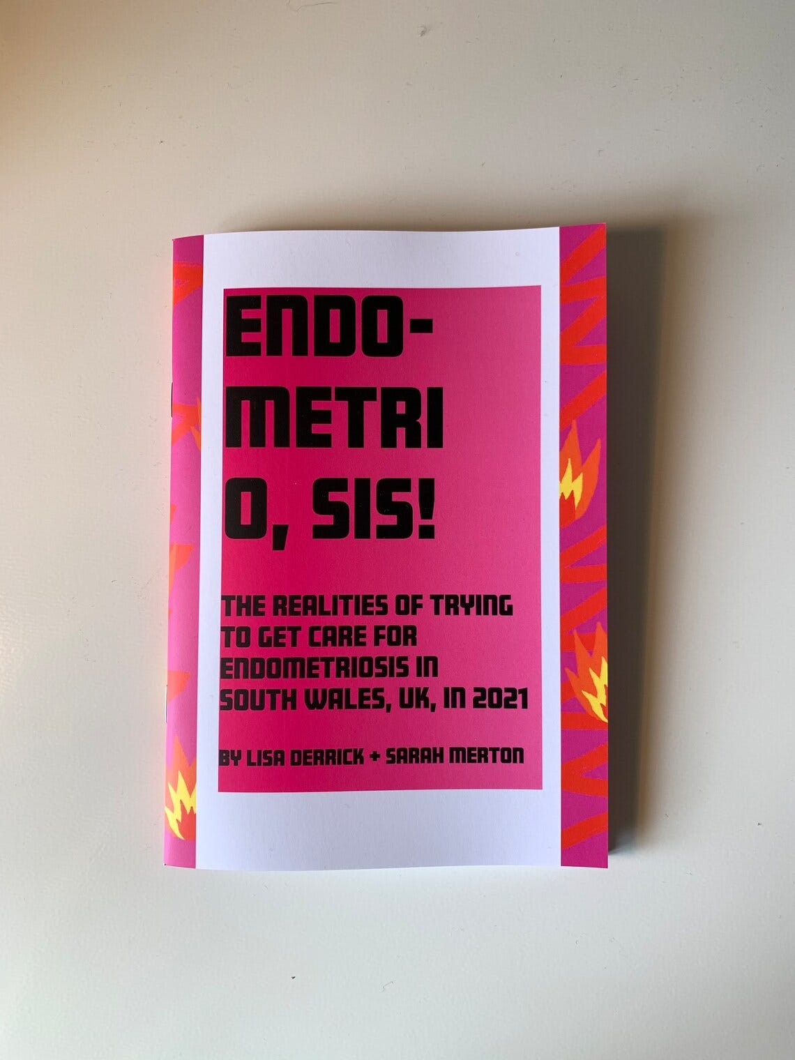 It is a picture of a zine with a bold pink cover and thick black type, the cover says, "Endometri O, Sis! The realities of trying to get care for endometriosis in South Wales, UK, in 2021."