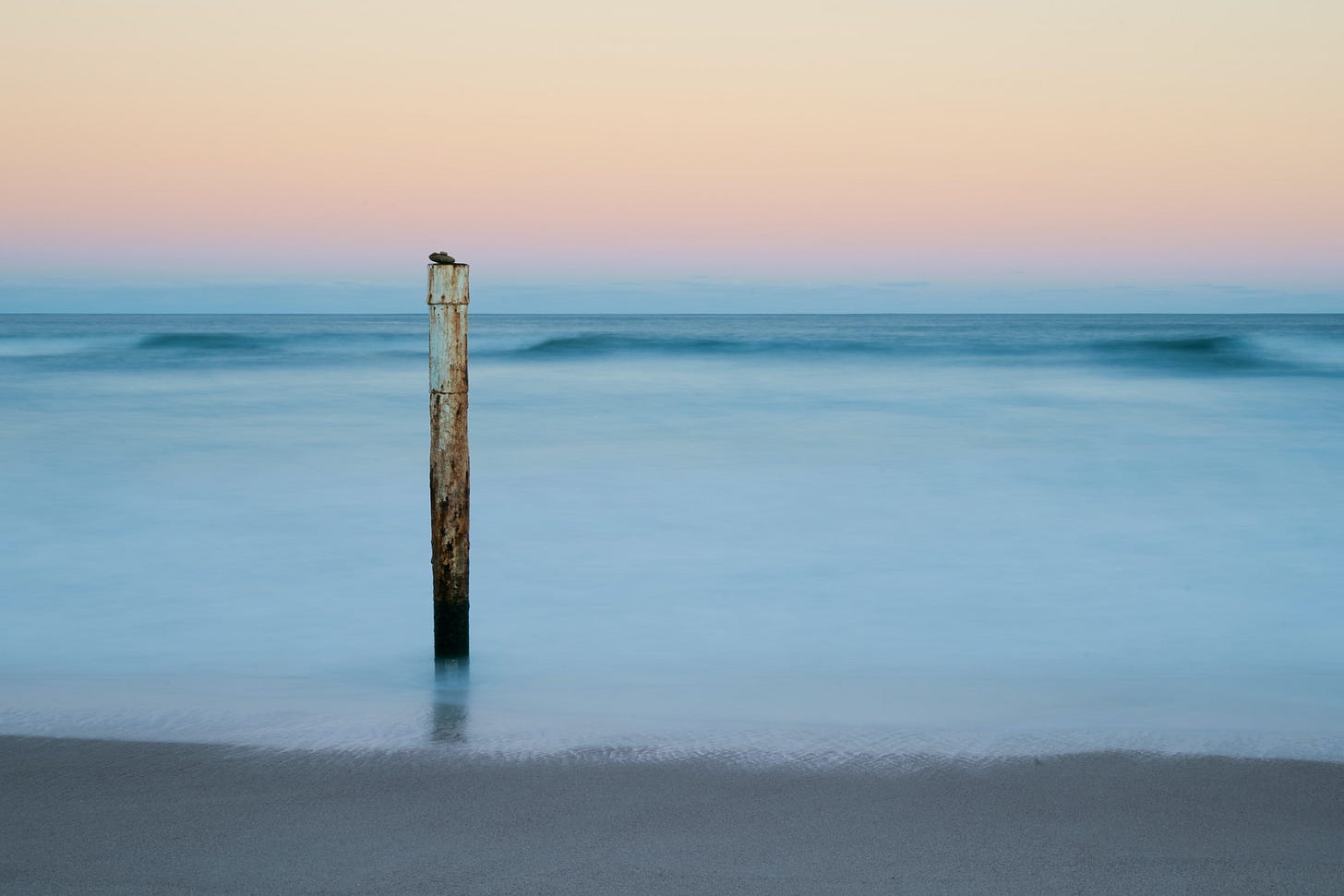pole sticking out of the sand and water on a beach pole sticking out of the sand and water on a beach