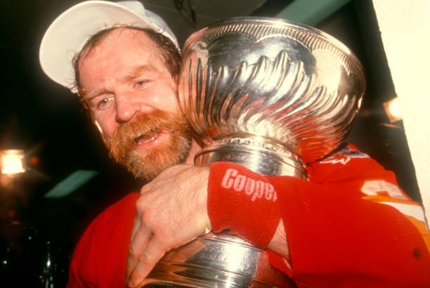 Lanny McDonald of the Calgary Flames hugs the Stanley Cup Trophy in the locker room after the Flames defeated the Montreal Canadiens in Game 6 of the...