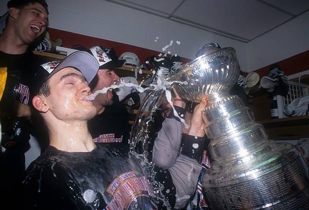 Bobby Holik of the New Jersey Devils celebrates with the Stanley Cup Trophy as he closes his eyes and spits a stream of champagne from his lips while...