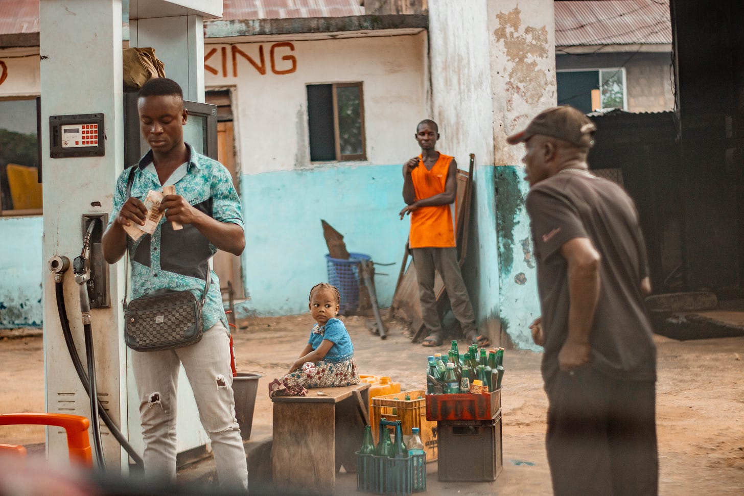 A man watching an old man approaching a vendor counting his money, a kid at his back in Calabar,: A photo by David Elikwu