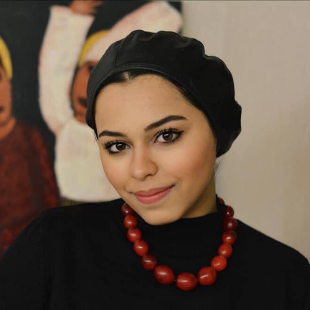May be an image of Malak Mattar, hair, headscarf, outerwear and jewelry