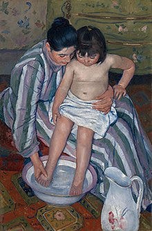 A mother dressed in a striped dress with long sleeves and turtleneck helps her small daughter wash her feet. She wears her shiny black hair in a loose bun and holds the child securely. The girl is sitting in her mother’s lap and her waist is wrapped in a white towel. She watches as her mother gently dips her small legs into the purple-rimmed glass bowl that stirs below with water. In the right-hand corner, a white water pitcher with different shades of pink flowers is standing on the orange-patterned carpet. In the background a yellow wardrobe with tiny flowers and golden handles sits against the flowery wallpaper. A mother dressed in a striped dress with long sleeves and turtleneck helps her small daughter wash her feet. She wears her shiny black hair in a loose bun and holds the child securely. The girl is sitting in her mother’s lap and her waist is wrapped in a white towel. She watches as her mother gently dips her small legs into the purple-rimmed glass bowl that stirs below with water. In the right-hand corner, a white water pitcher with different shades of pink flowers is standing on the orange-patterned carpet. In the background a yellow wardrobe with tiny flowers and golden handles sits against the flowery wallpaper.