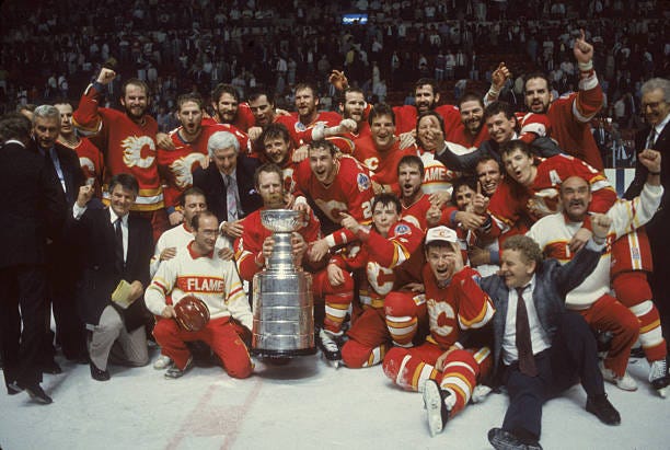 Team portrait of the players and staff of the Calgary Flames as they pose on the ice with the Stanley Cup trophy after they defeated the Montreal...