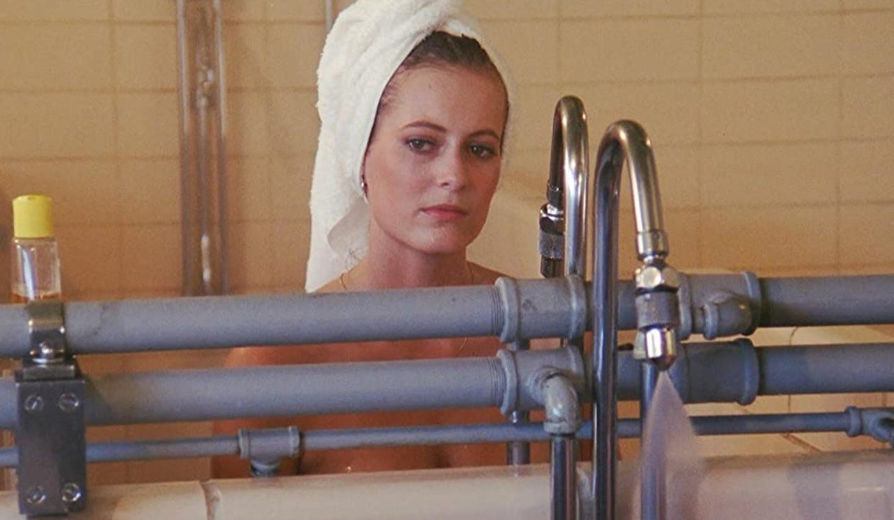 Valerie stands in the lockers showers with a towel wrapped around her hair looking longingly off camera.