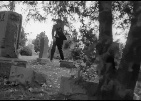 A zombie stumbles through a graveyard. From Night of the Living Dead. [gif]