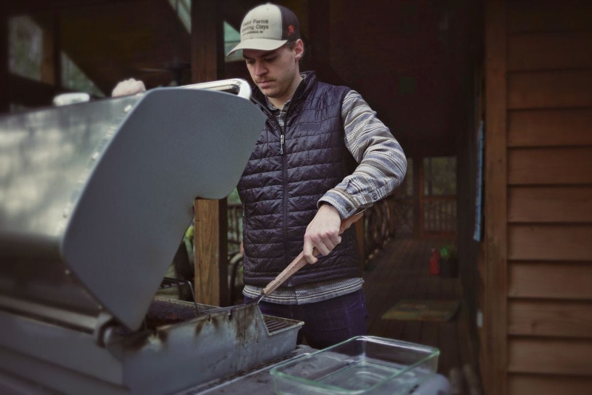 ryan wears a patagonia nano puff vest while grilling steaks