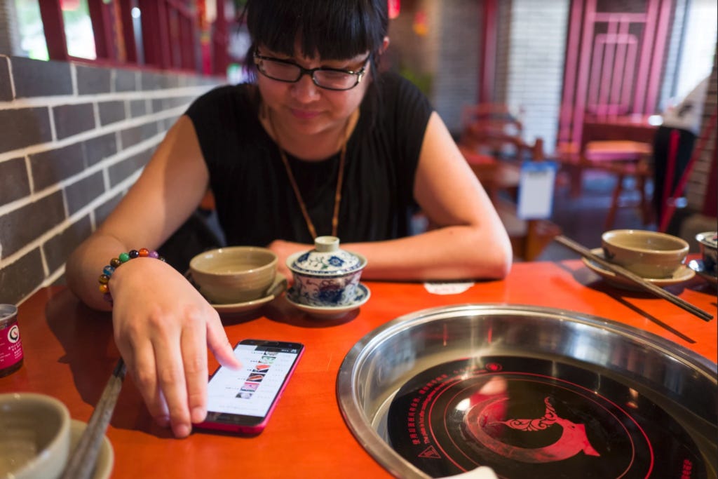 An Xiao Mina sitting at a hot pot table and scrolling through a phone An Xiao Mina sitting at a hot pot table and scrolling through a phone