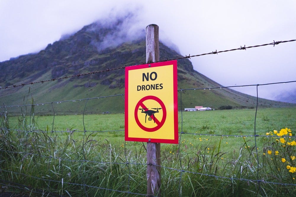 no drones signage on brown wooden post across mountain with fogs no drones signage on brown wooden post across mountain with fogs