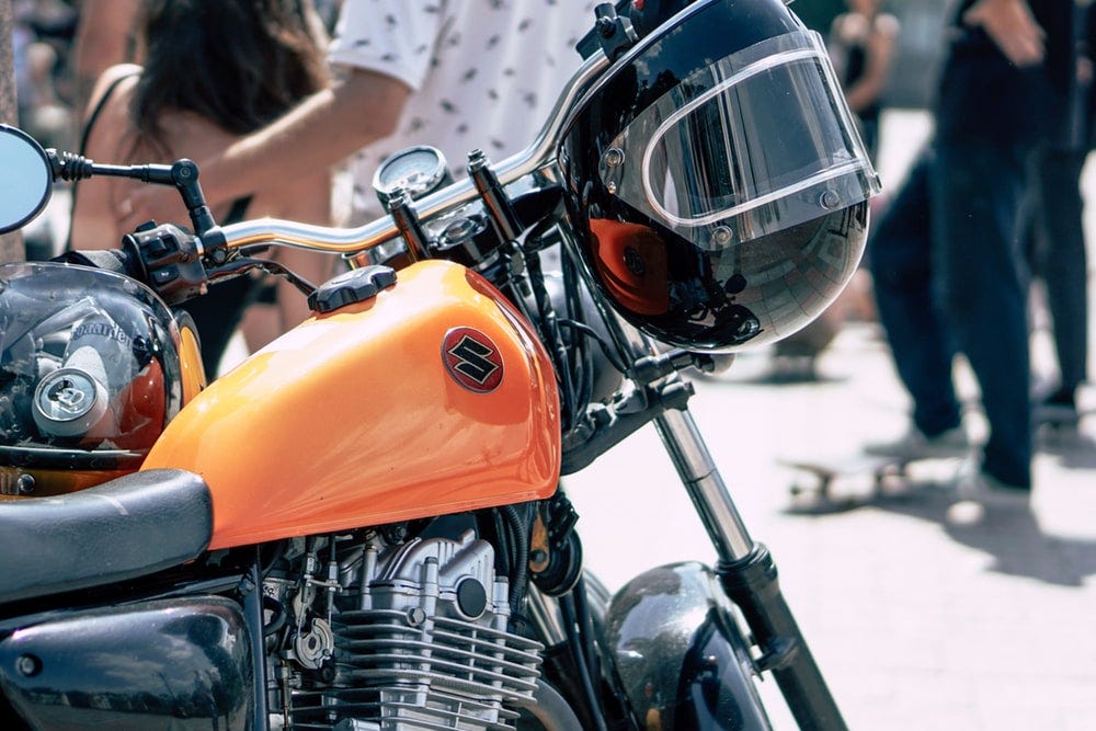 black helmet hanging on black and orange Suzuki motorcycle black helmet hanging on black and orange Suzuki motorcycle