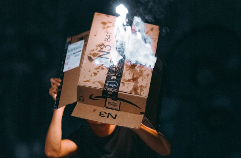 A man lights a cardboard Amazon box on fire. A man lights a cardboard Amazon box on fire.