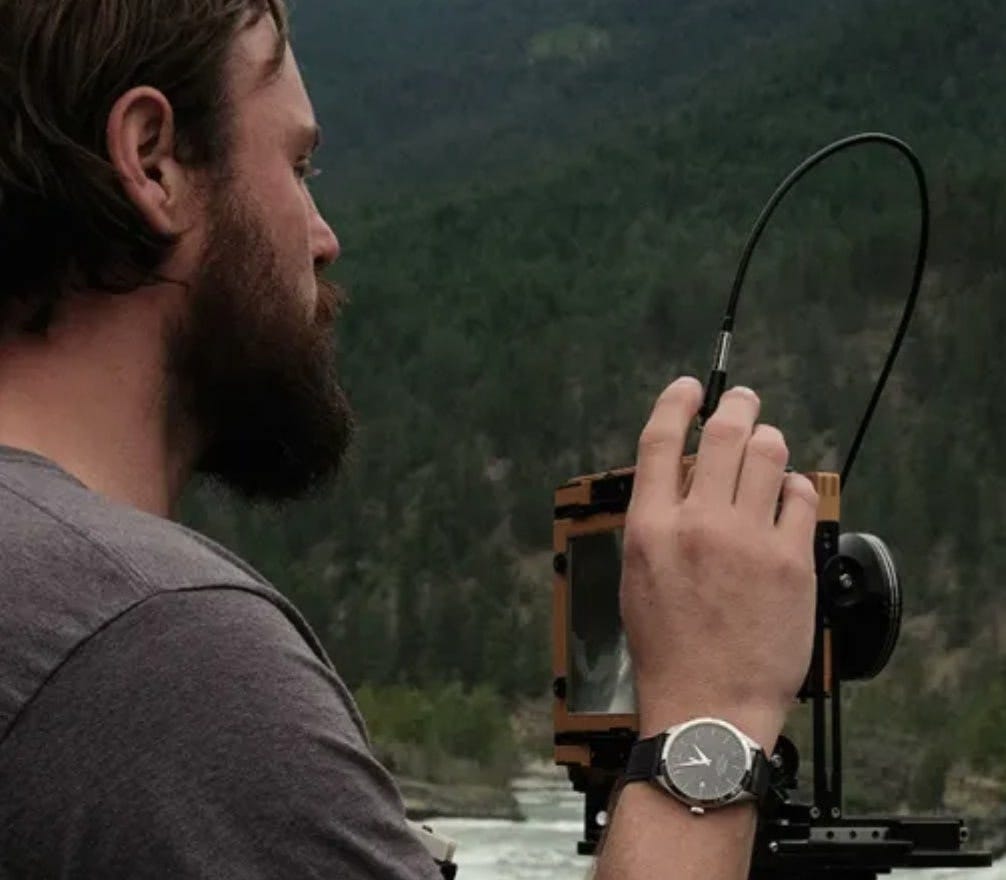 bryan schutmaat wearing the Timex american documents watch while he takes a photo of a river