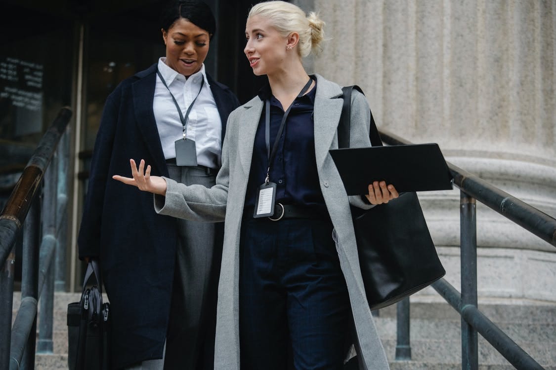 Content diverse female coworkers leaving office building together Content diverse female coworkers leaving office building together