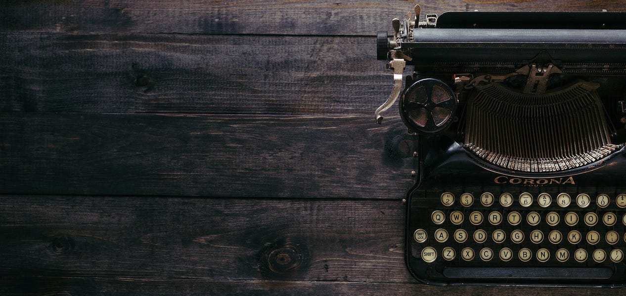 An old, mechanical typewriter sitting on a wooden table