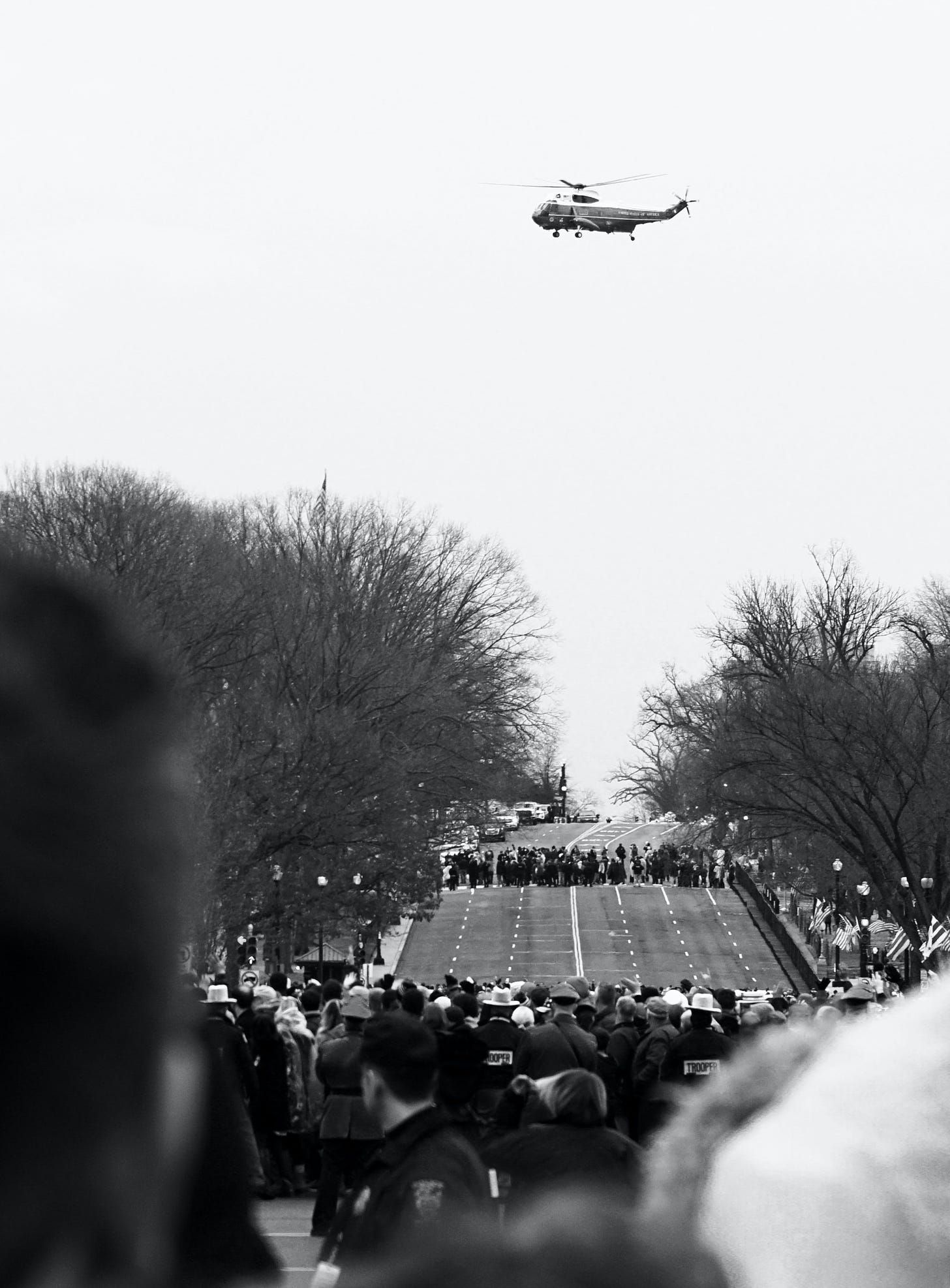 Photo of a government helicopter over the heads of people gathered in a street.