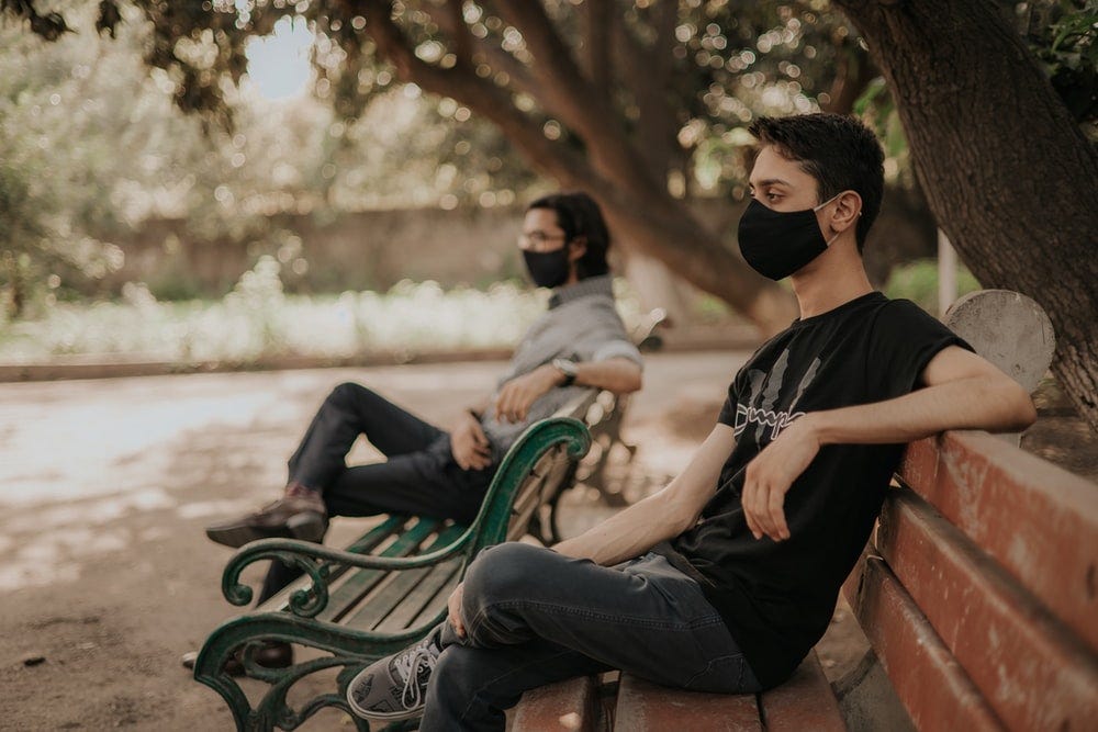 man in black crew neck t-shirt sitting on green bench during daytime man in black crew neck t-shirt sitting on green bench during daytime