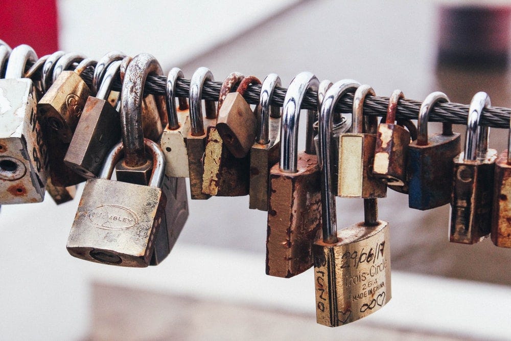 shallow focus photography of padlocks in steel cable shallow focus photography of padlocks in steel cable