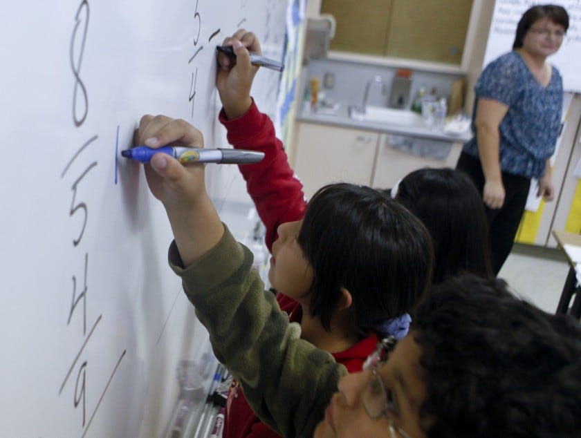 Students at Los Angeles Elementary School solve math problems at a whiteboard.