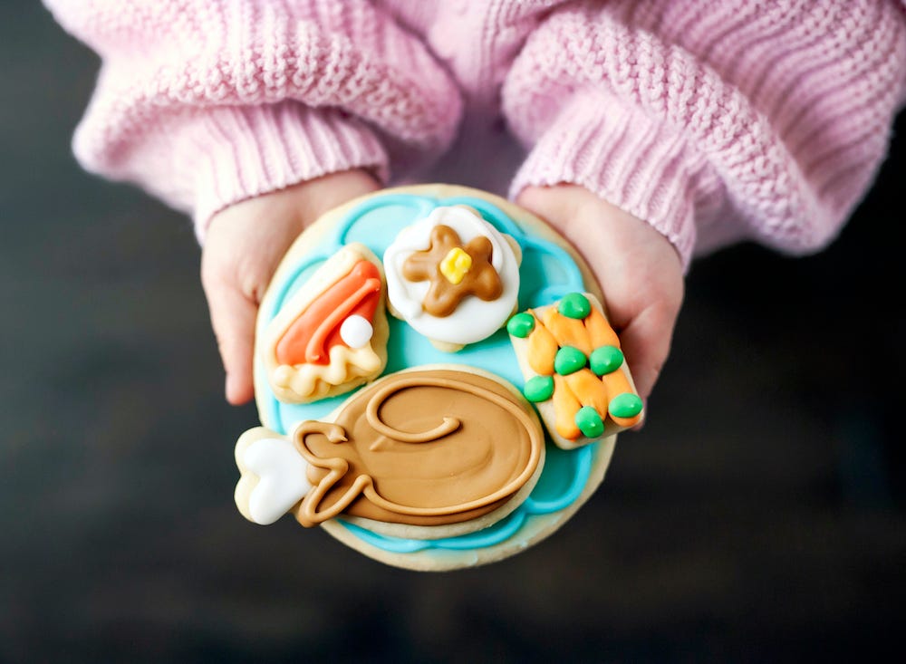 child's hands holding a cookie with a thanksgiving dinner on top