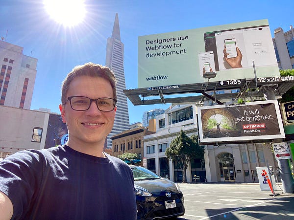 Selfie in front of the Transamerica Building with a Webflow billboard in front of it reading “Designers use Webflow for development”

Right below it is a billboard reading “it will get brighter. Optimism. Pass it on.”