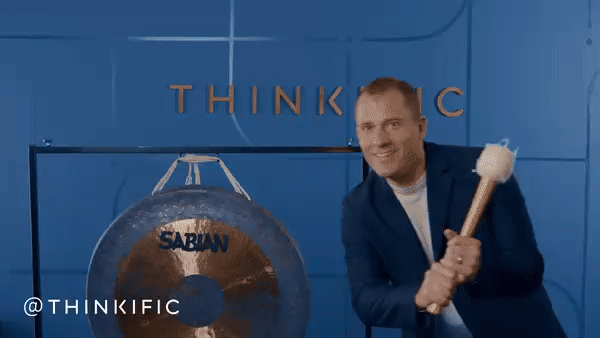 Thinkific CEO hitting a gong while blue confetti rains down